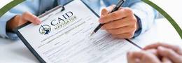 Hands completing a Medicaid application on a clipboard